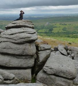 Person sitting on top of a huge granite rock